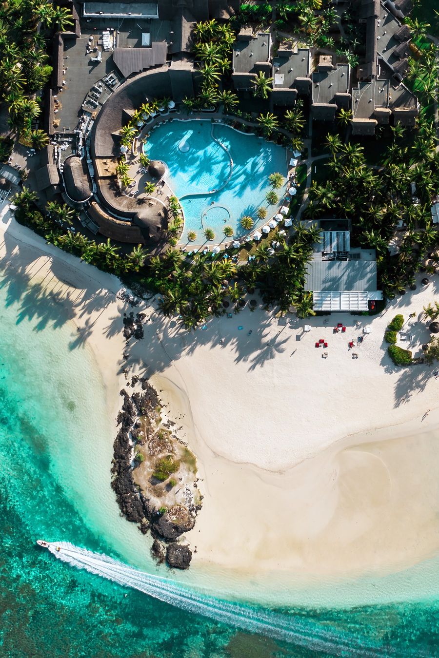 Vista aérea de resort com piscina, praia de areia branca e mar azul-turquesa