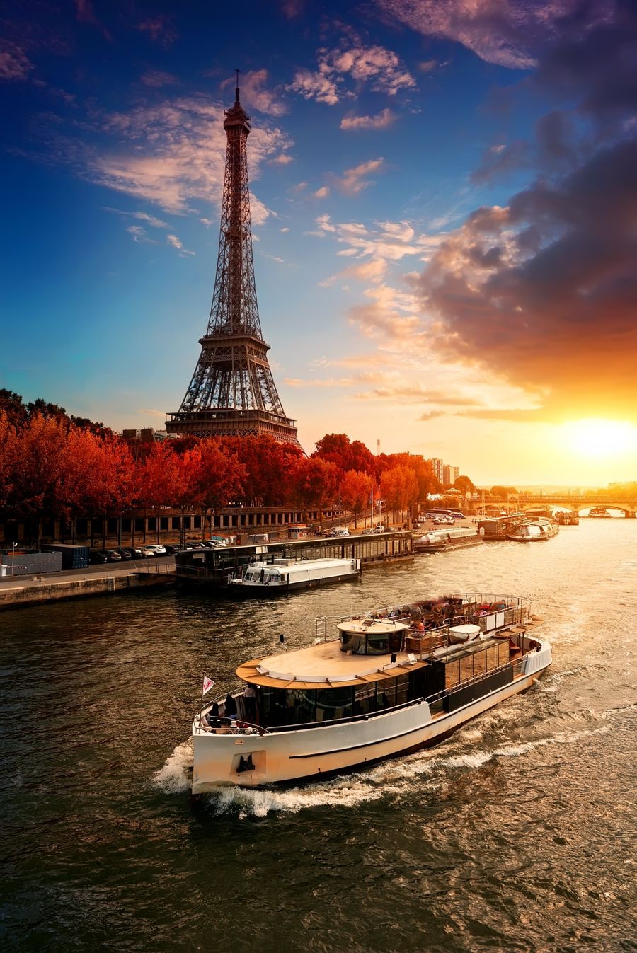 Barco navegando no rio Sena com a Torre Eiffel ao pôr do sol